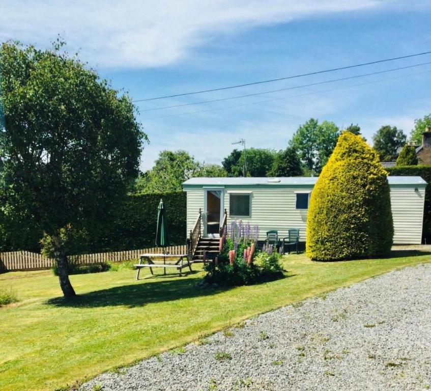 a caravan in a yard with a bench and flowers at Forest View - Adults Only - Maximum 2 Guests in Drumnadrochit