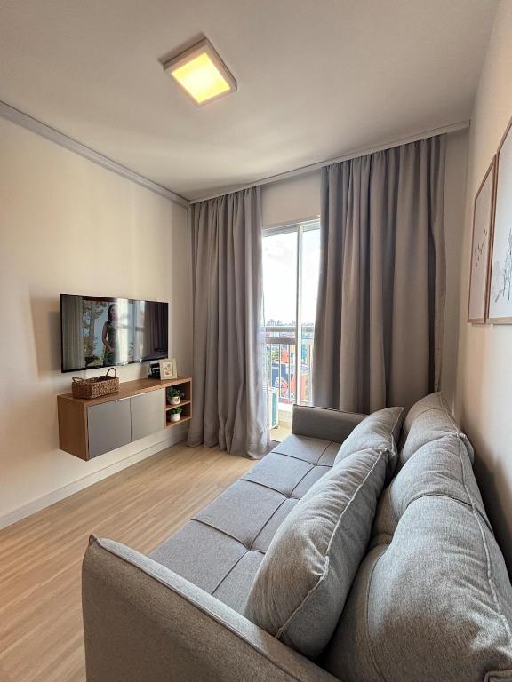 a living room with a couch and a television at City Core 2 Bedrooms by AP Smart in Campinas