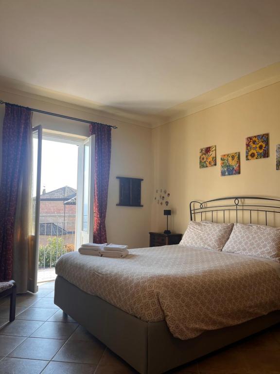 a bedroom with a bed and a large window at An tij slè - Nel cuore del borgo in Guarene