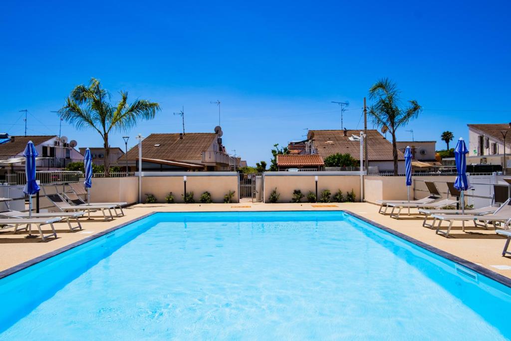 a swimming pool with lounge chairs and a resort at Residence Casuzze in Marina di Ragusa