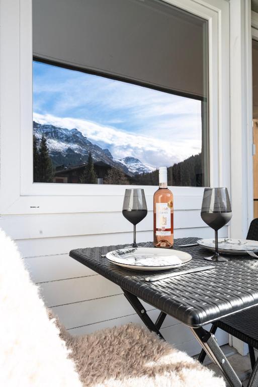 a table with a bottle of wine and two glasses at Superbe Studio Morgins au Pied des Pistes avec Piscine in Morgins