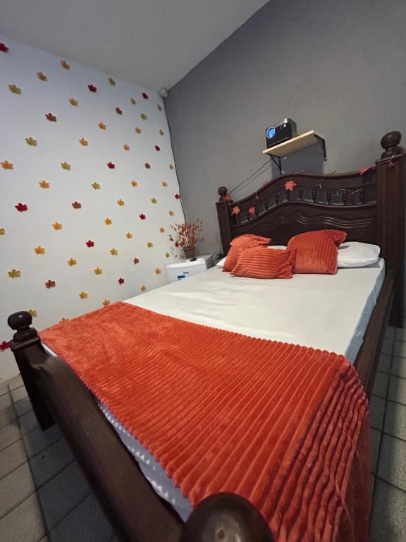 a bedroom with a large bed with an orange blanket at Green Suíte Comfort in Garanhuns