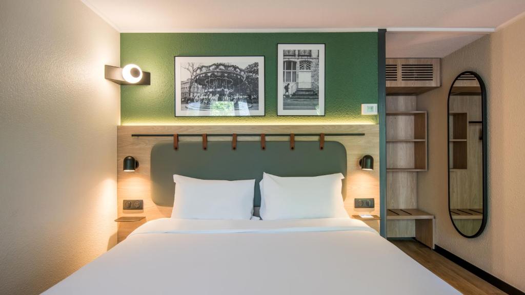 a bedroom with a large bed and a green wall at Campanile NATURE - Martigues in Martigues