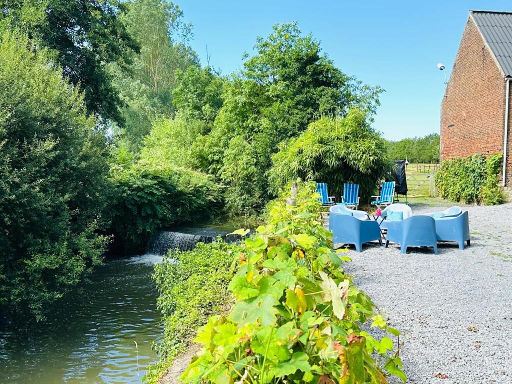 a garden with tables and chairs next to a river at Moulin de Meeffe in Wasseiges