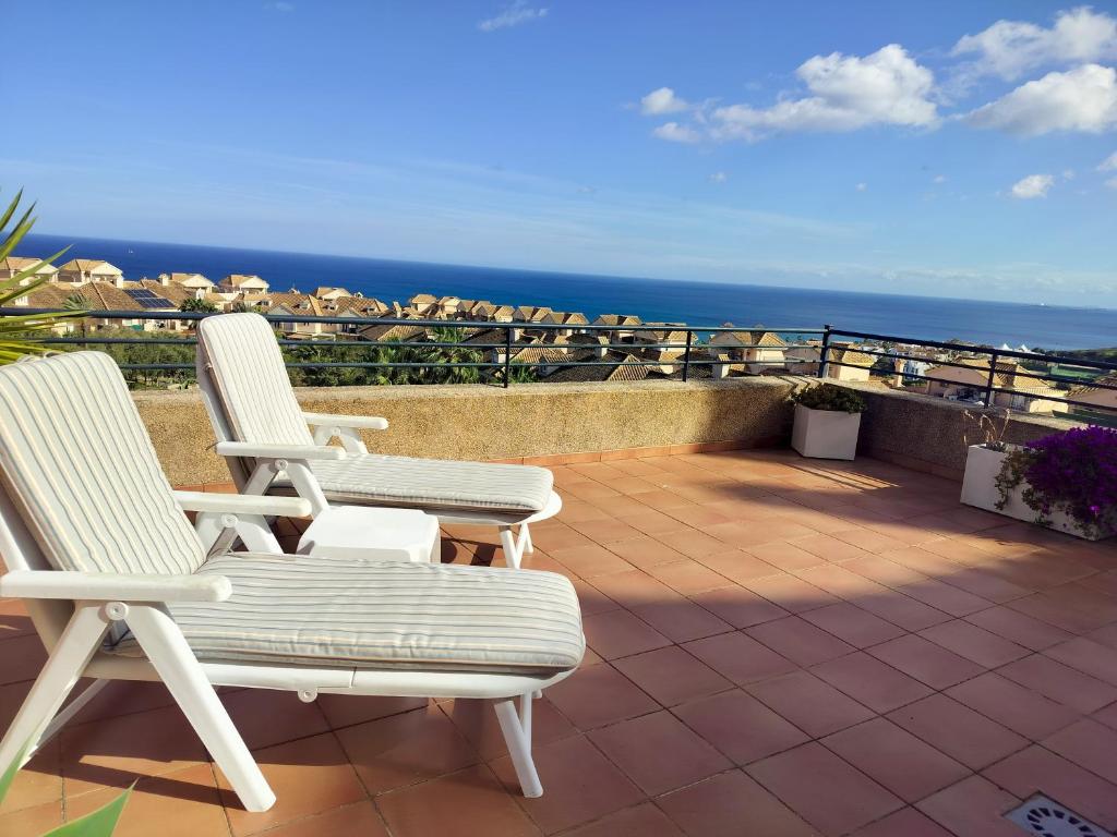 two white chairs sitting on a patio overlooking the ocean at Anitas Seaview Paradise in La Línea de la Concepción