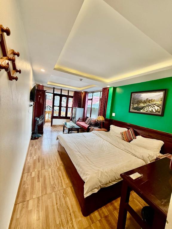 a bedroom with a large bed with a green wall at Khách Sạn Nguyễn Hùng in Sapa