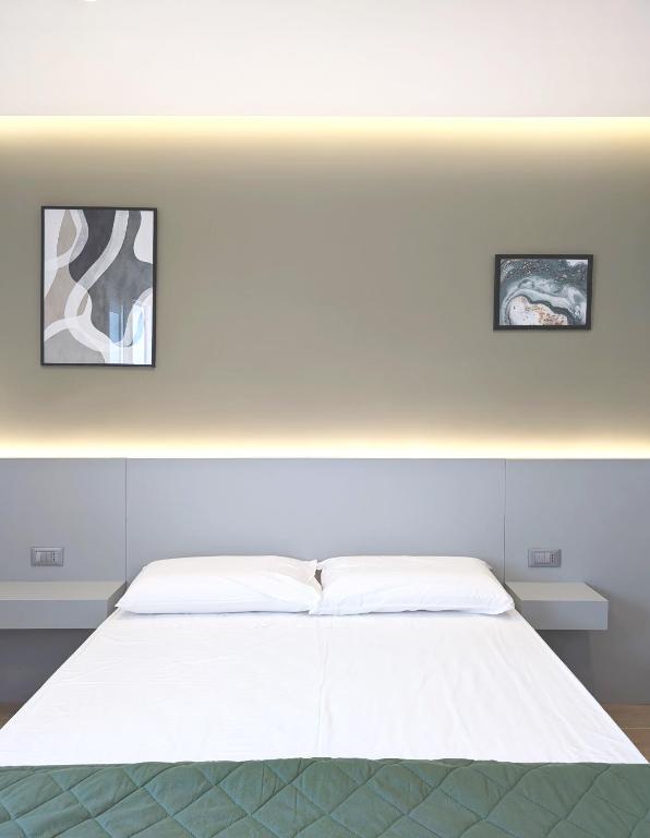 a white bed in a room with two pictures on the wall at The Superhost - IL Lux in Crotone
