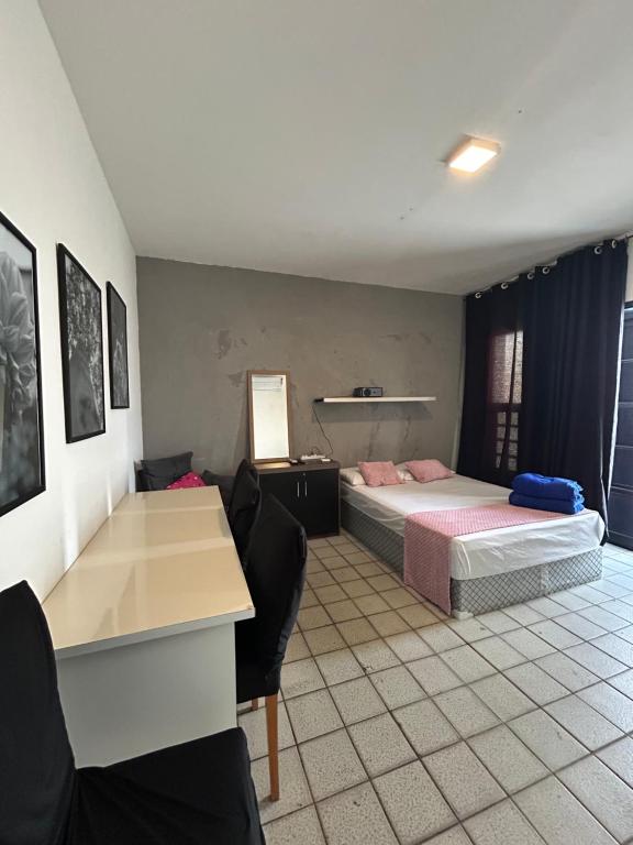 a bedroom with a bed and a desk and chairs at Grey Flat Comfort in Garanhuns