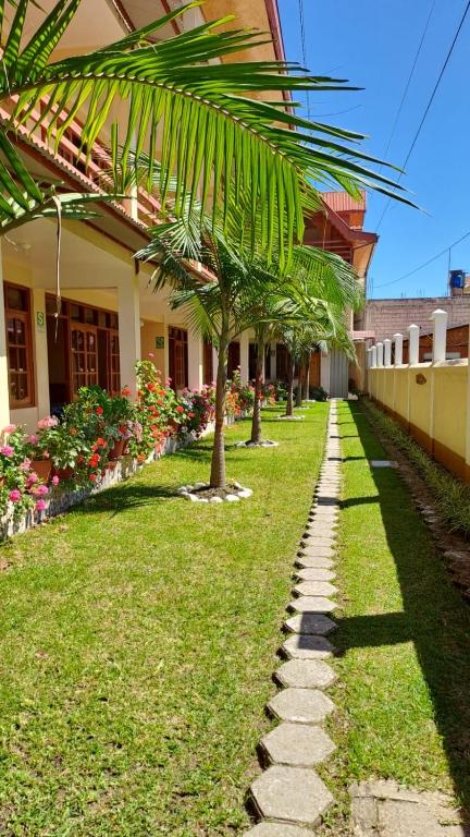 a walkway in front of a building with palm trees at Hospedaje El Manantial in Chontabamba