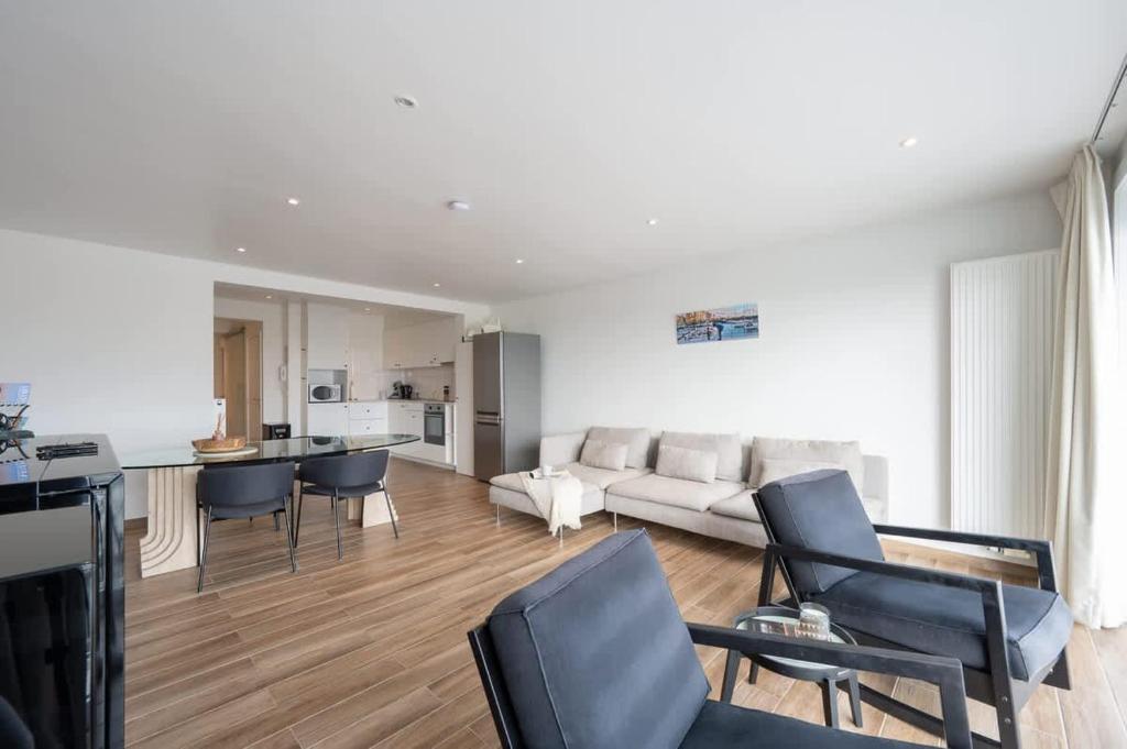 a living room with a couch and chairs and a kitchen at 2-slaapkamer appartement met zicht op de Haven in Blankenberge