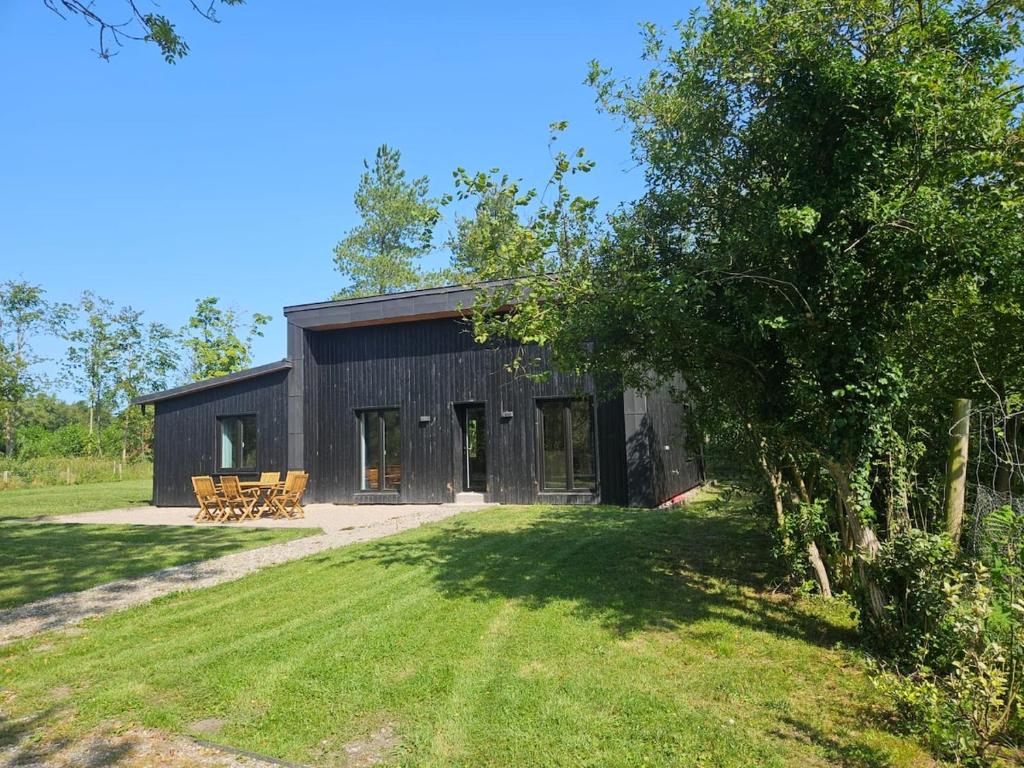 a black barn with benches in a yard at Gîtes Prestige LETENDART in Saint-Quentin-en-Tourmont