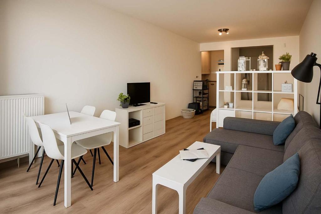 a living room with a couch and a table at Casiola - Beach Studio with Balcony & Sea View in Zeebrugge