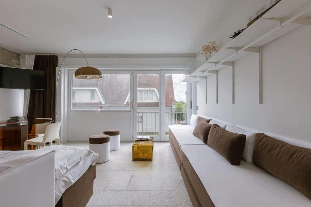 a living room with white furniture and a large window at Sea views - beachfront - in the heart of Knokke-Heist in Knokke-Heist