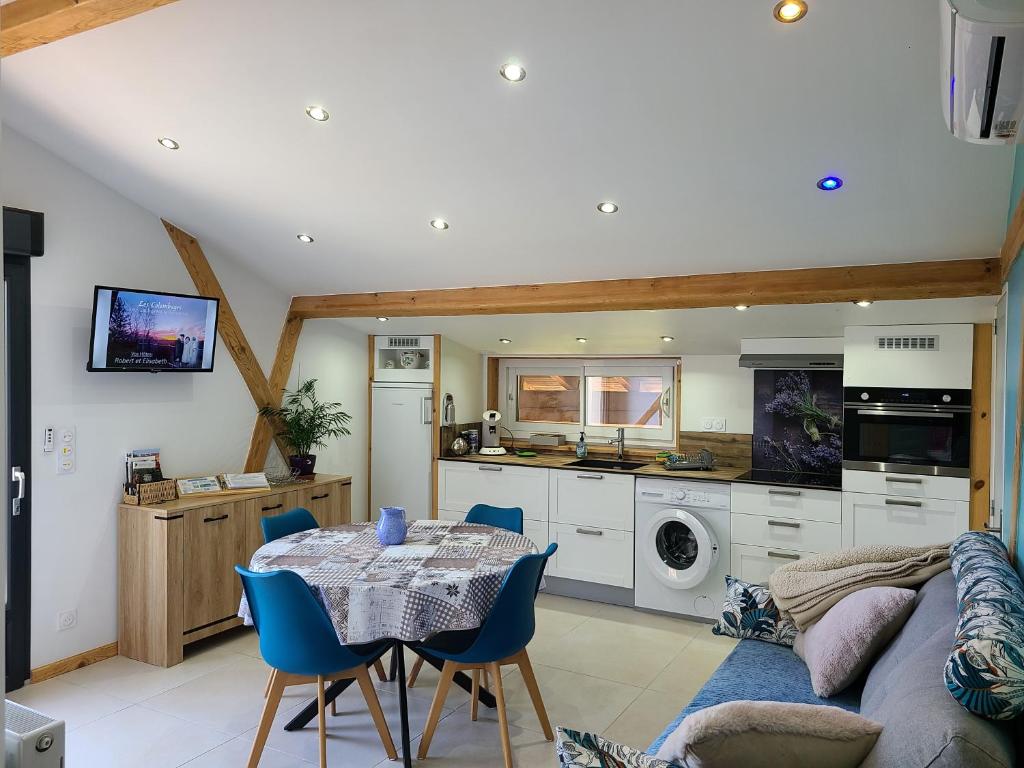 a kitchen and living room with a table and blue chairs at - - - - -Les Colombages - - - - Chambre d'hôtes-Gîte- Classement Gîte 3 étoiles in Mirepoix