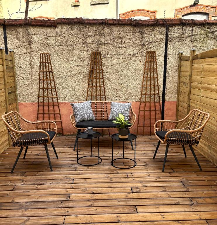 three chairs and a table on a patio at Le jardin secret in Reims