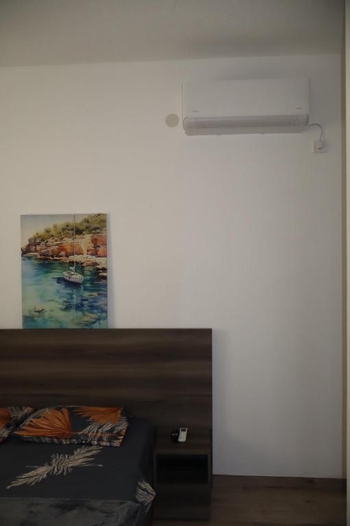 a bedroom with a bed and a painting on the wall at Apartmani XS in Sutomore