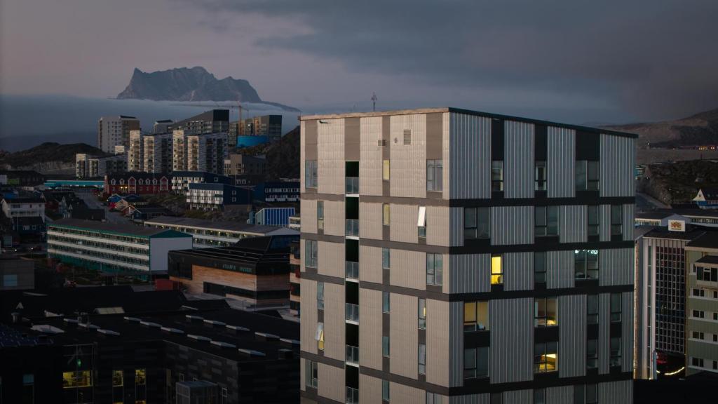 a tall building in front of a city at Hotel Aurora Apartments in Nuuk