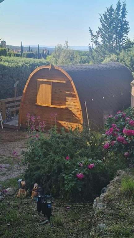 a small wooden tent in a yard with flowers at La Cabane douillette in Aups