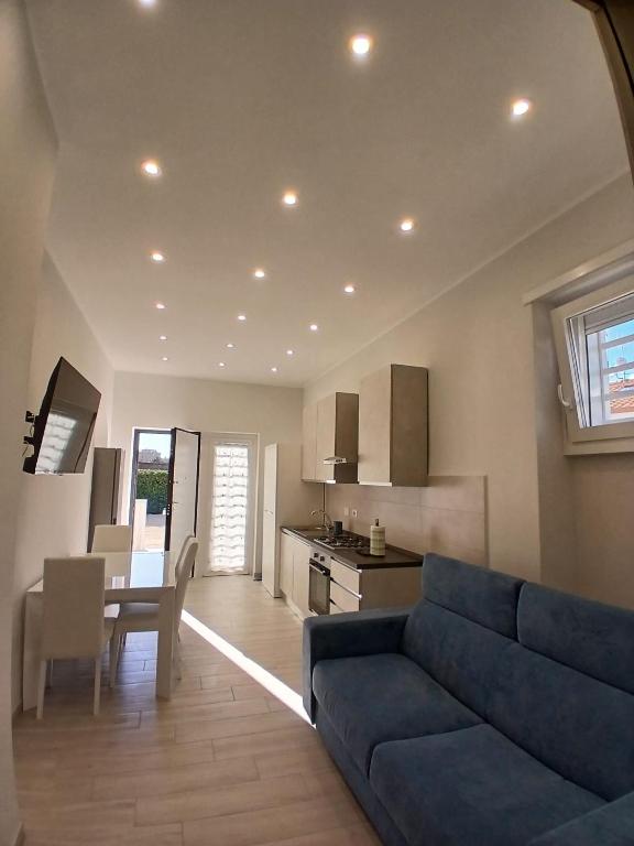 a living room with a blue couch and a kitchen at Grazia Nest in Ciampino