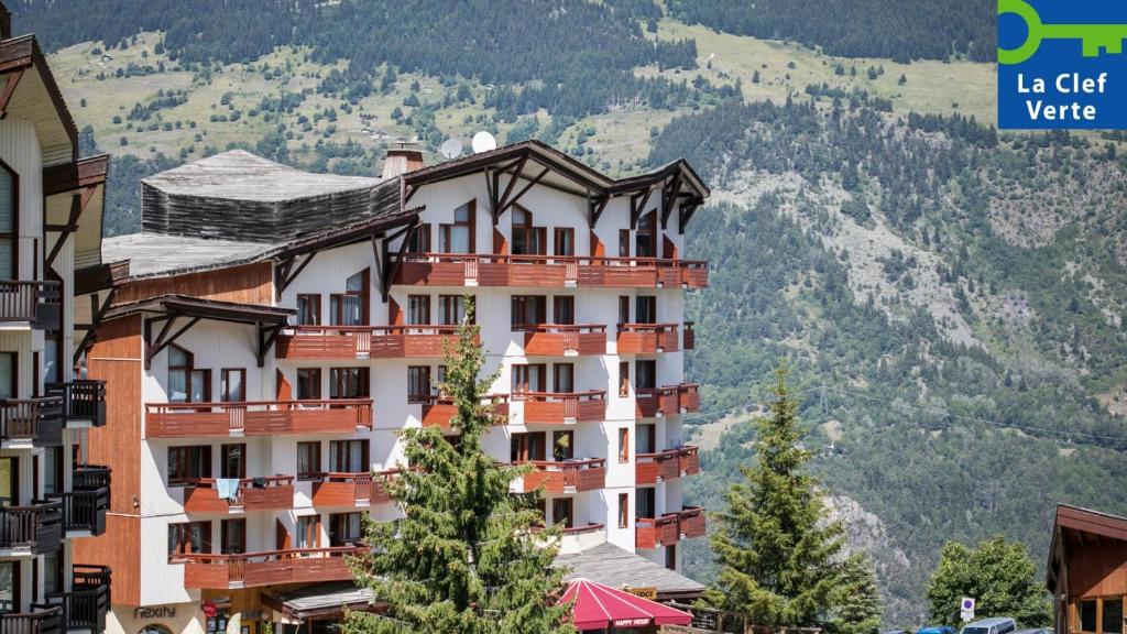 a tall building with trees in front of a mountain at Résidence Pierre & Vacances Le Britania in La Tania