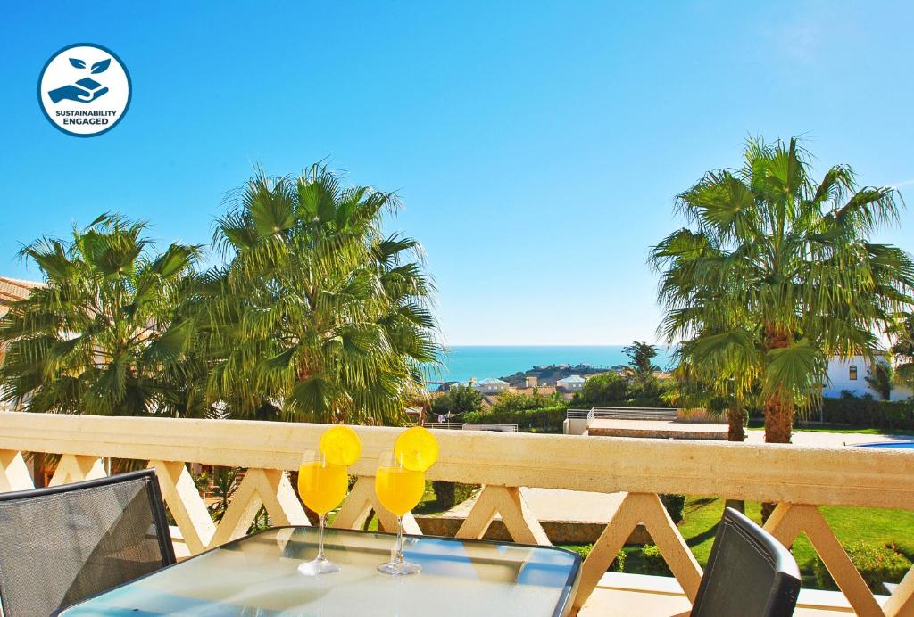 a table with two glasses on a balcony with palm trees at Townhouse Mar 2 - Moradia com BBQ e vista mar - Albufeira in Albufeira