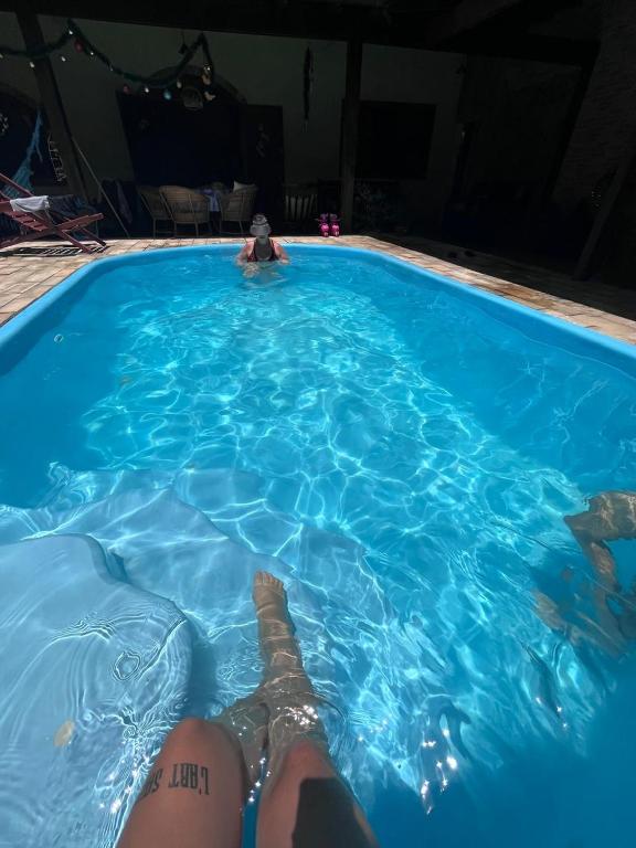 a person laying in a blue swimming pool at Casa com área de lazer em Xerém in Duque de Caxias