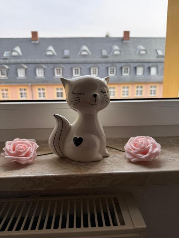a white cat figurine sitting on a shelf in front of a window at Lindenstraße in Aue-Bad Schlema