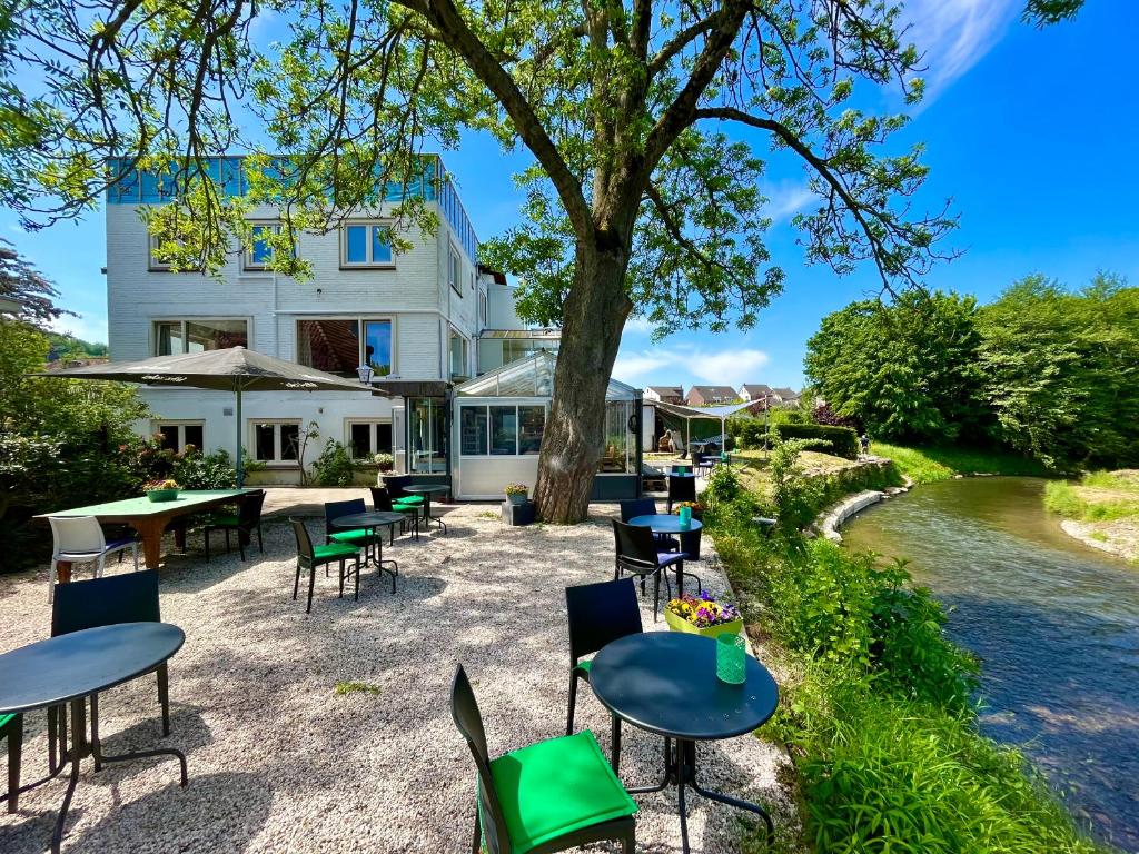 a building with tables and chairs next to a river at Boutiquehotel B&B the SJinn in Schin op Geul