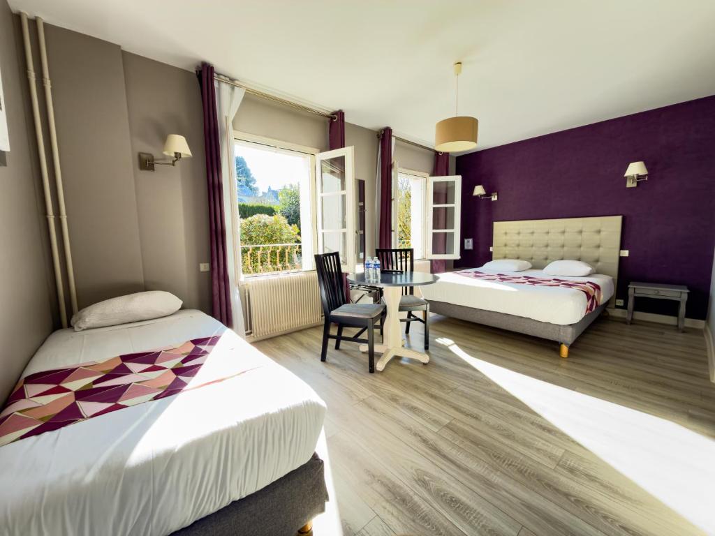 a hotel room with two beds and a table and chairs at Logis Hotel Restaurant des Voyageurs in Tarnac