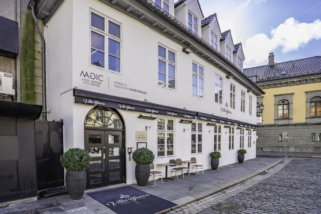 ein weißes Gebäude mit einem Tisch davor in der Unterkunft Magic Hotel Bergen City Center, a member of Radisson Individuals in Bergen