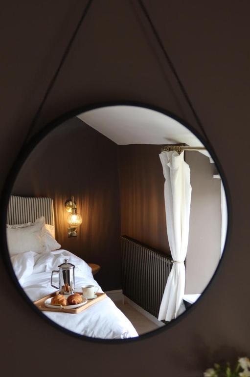 a reflection of a bed in a round mirror at Plum Cottage in Cottesmore