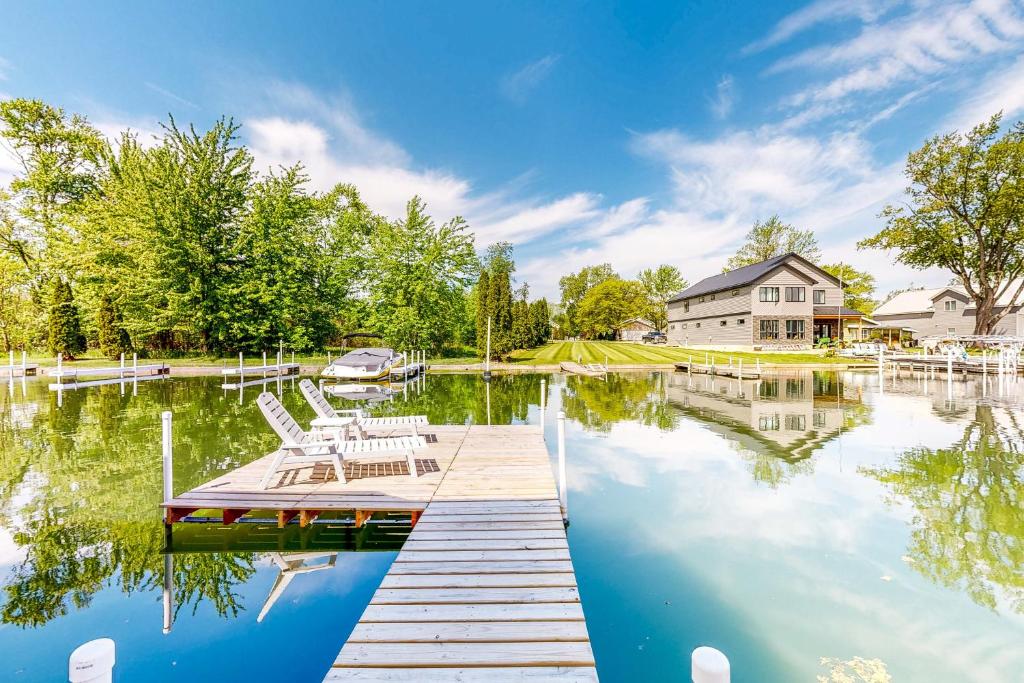 a dock with chairs and a house on a lake at The Boat House w/ Dock: Enjoy Lake Life! in North Webster