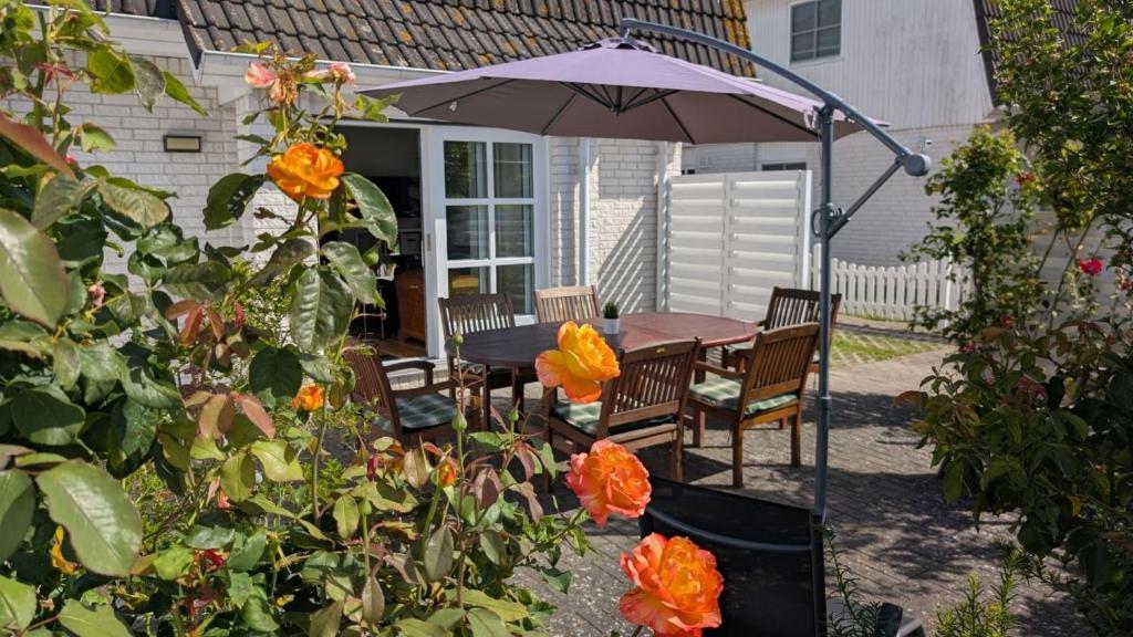a patio with a table and chairs under an umbrella at am-hoeben in Fehmarn