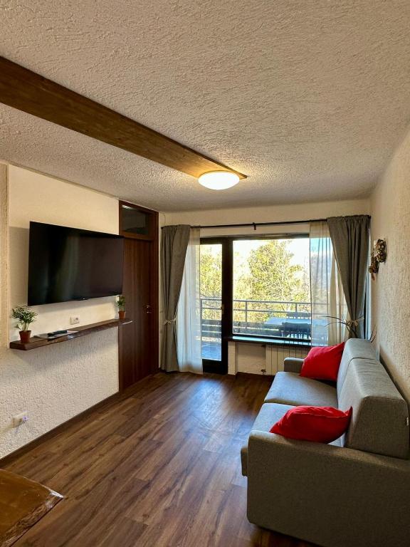 a living room with a couch and a flat screen tv at Montecampione Prati B in Pian Camuno
