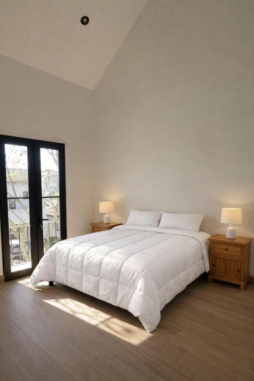 a white bedroom with a large bed and a window at Casa Olivos in Ciudad Vieja