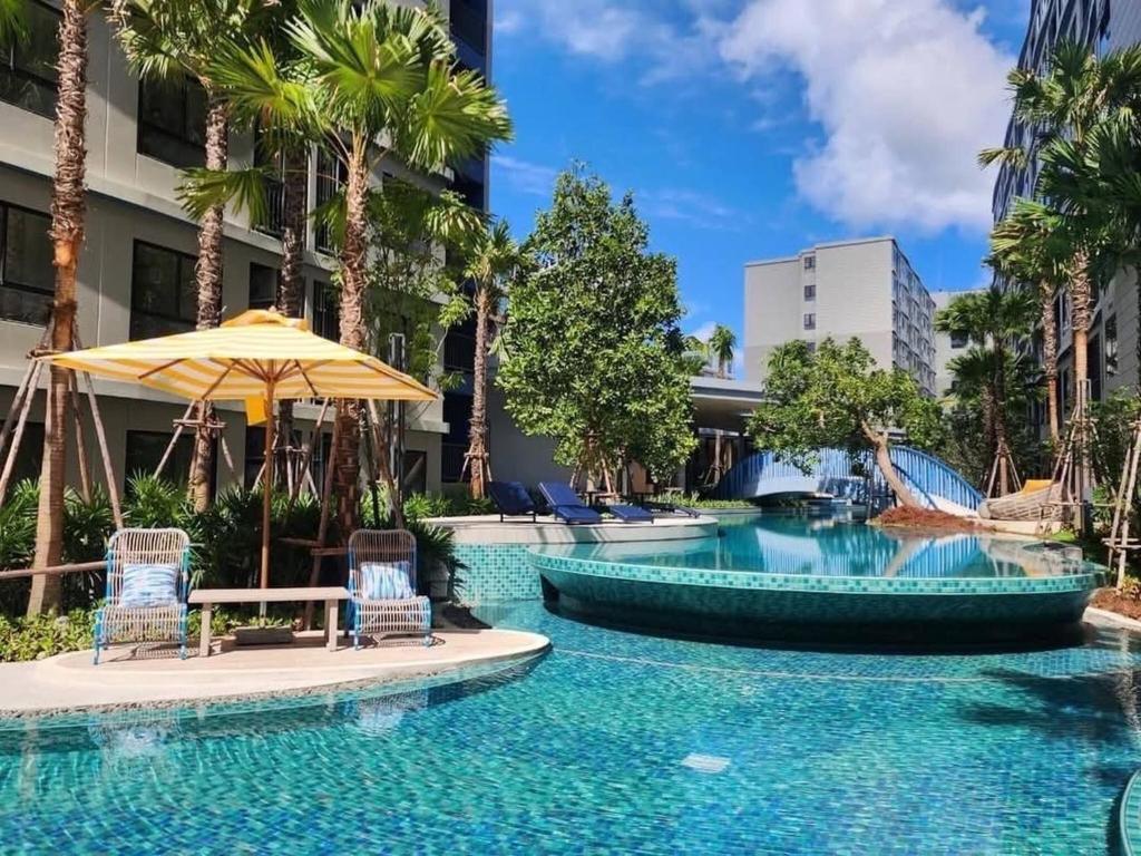 a pool at a hotel with chairs and an umbrella at Dcondo Reef kathu Patong in Kathu