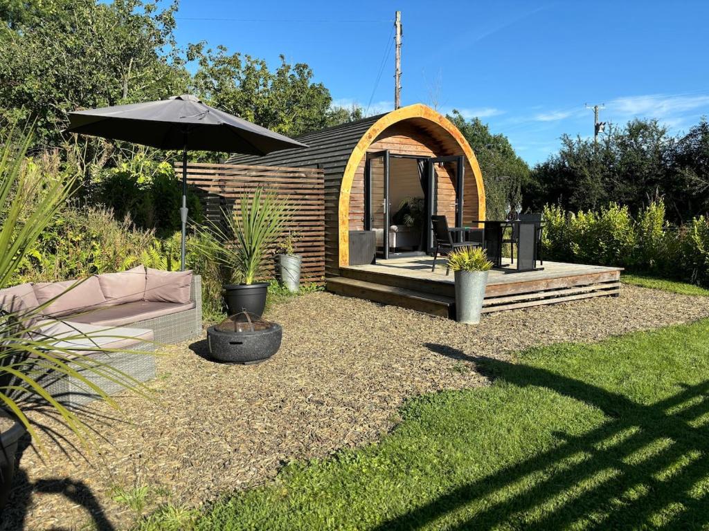 a small cabin with an umbrella in a yard at Glamping pod with en-suite & underfloor heating in Haverfordwest