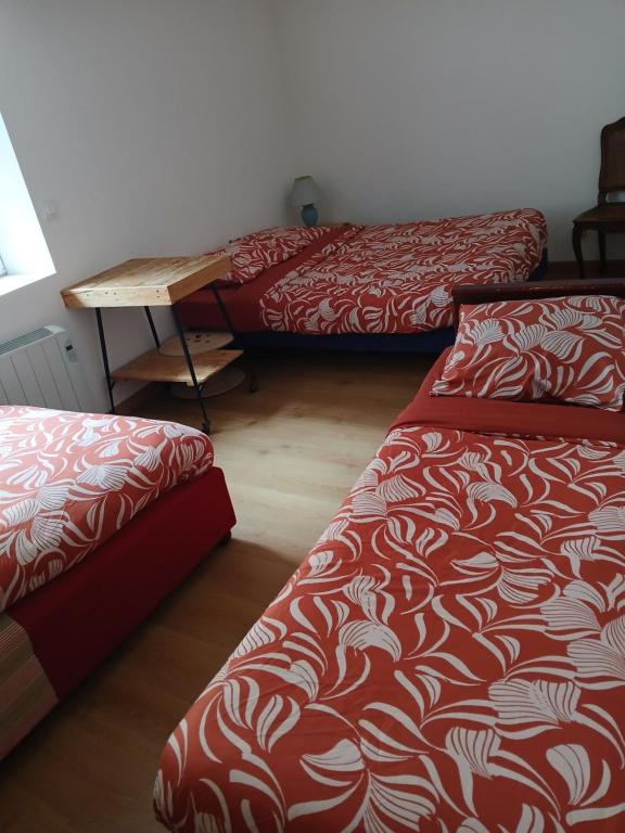 a room with three beds and a wooden table at Chic et relax familial in Montmarault
