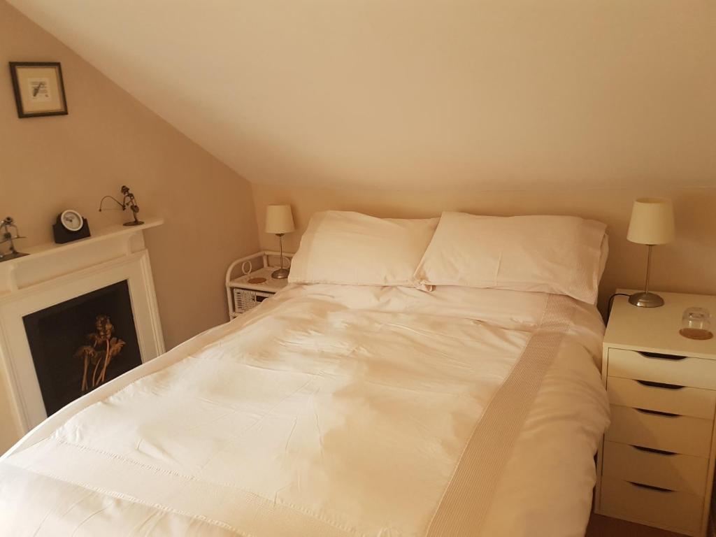 a bed with white sheets and pillows in a bedroom at Lammas Park House in Dawlish