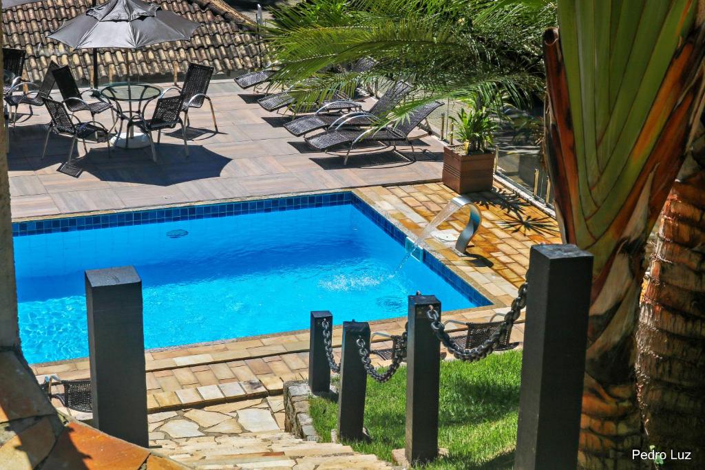 a swimming pool in a yard with chairs around it at Pousada Reserva Penedo in Penedo