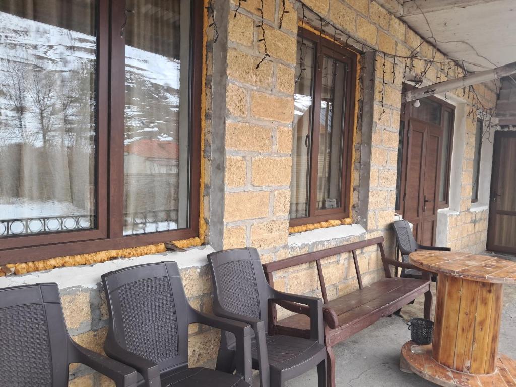 a bench and chairs on a porch with a table and windows at Hotel kazbegi1 in Ach'khoti