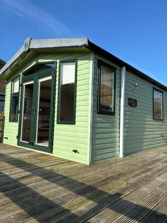 a green building with a door on a deck at Bordeaux sea view no 9 in Ardentinny