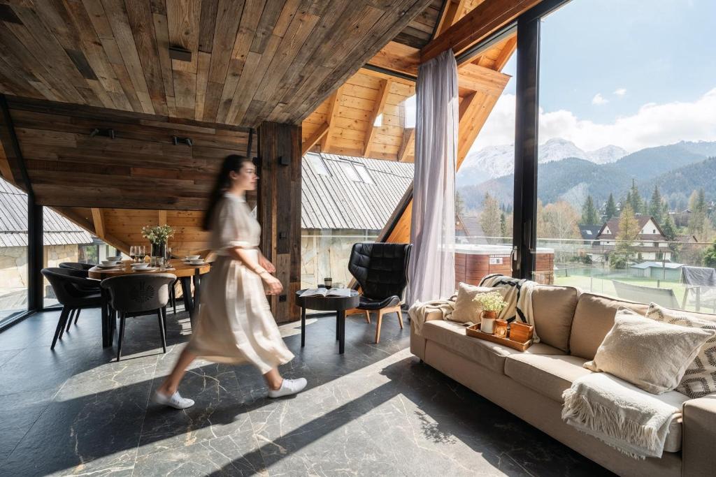 a woman walking through a living room with a couch at come home - bespoke villa in Kościelisko