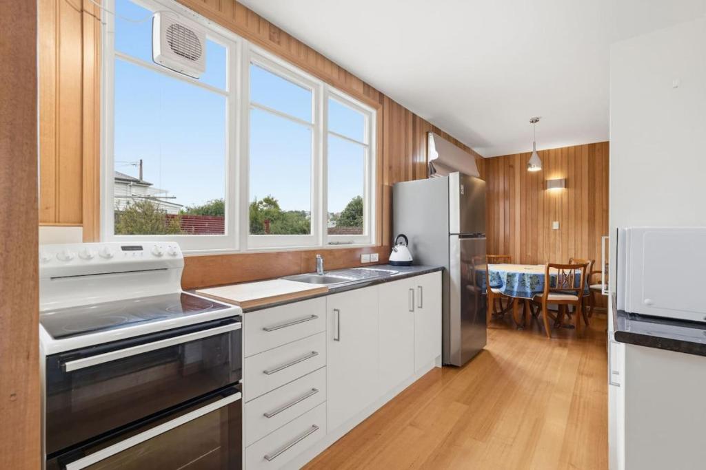 a kitchen with white cabinets and a stainless steel refrigerator at Charming Sandy Bay Cottage in Sandy Bay