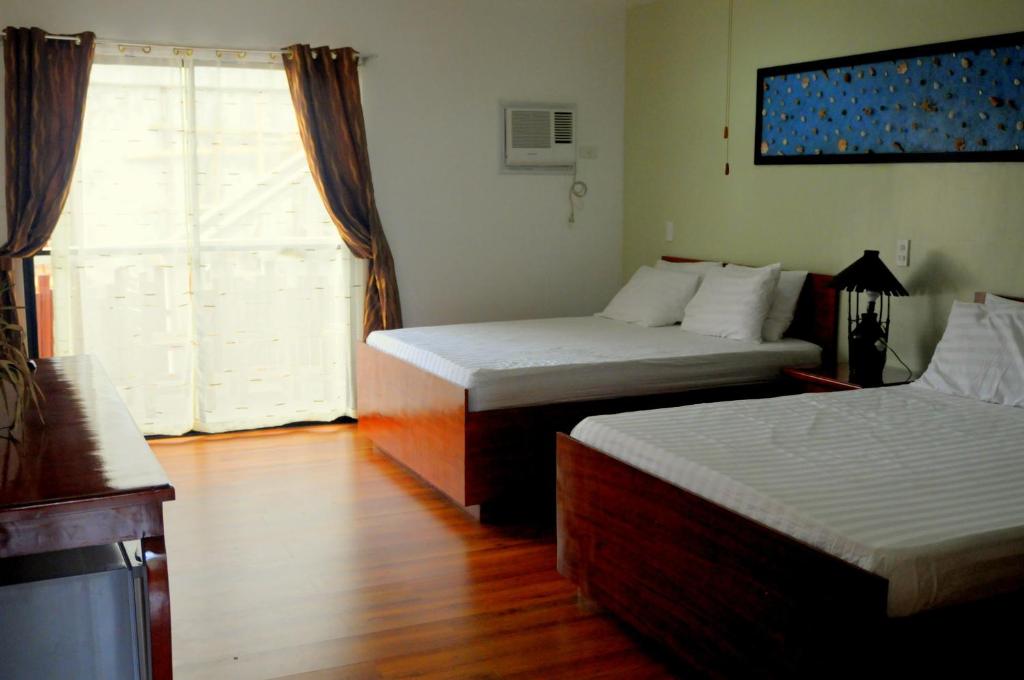 Habitación de hotel con 2 camas y ventana en Oasis Resort and Spa en Boracay