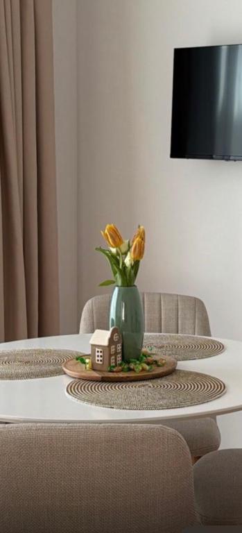 a table with a green vase with flowers in it at Arya Thermalis in Baile Felix