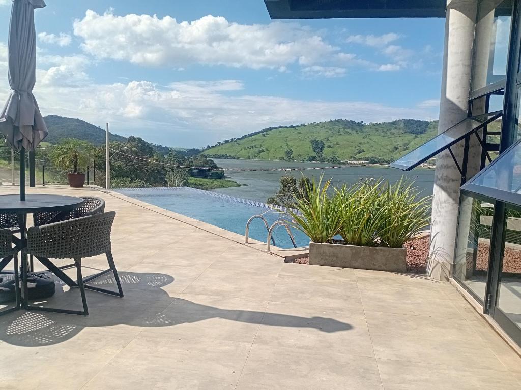 a patio with a table and a view of a lake at Pousada Varandas do Lago in Capitólio