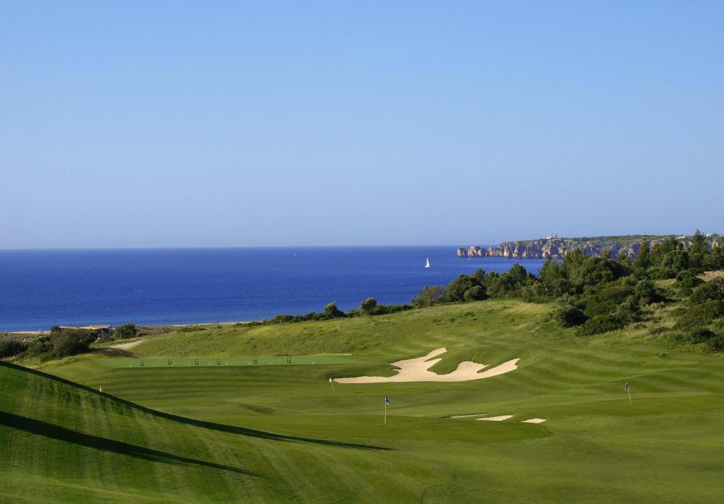 a green golf course with the ocean in the background at Palmares Beach House Hotel - Adults Only in Lagos