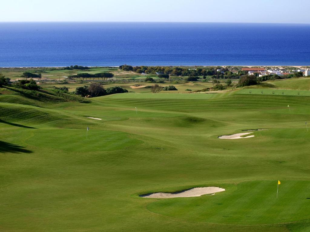 a green golf course with the ocean in the background at Palmares Beach House Hotel - Adults Only in Lagos