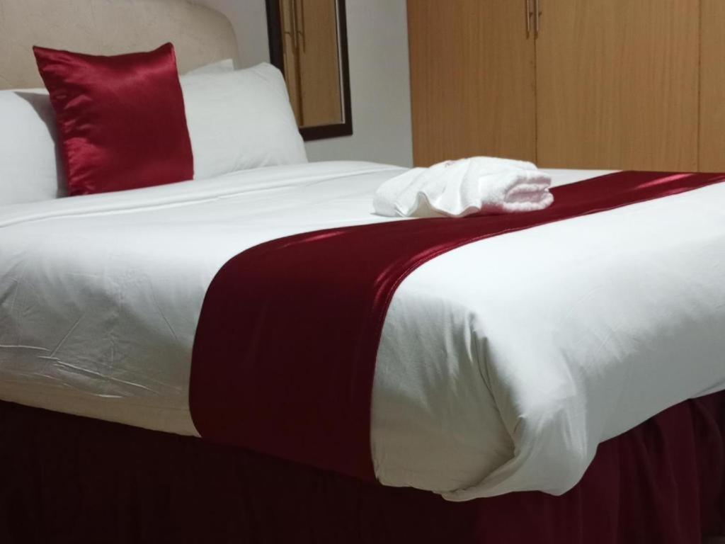 a large bed with red and white sheets and pillows at Jojos Palace Hotel - Gulu in Gulu